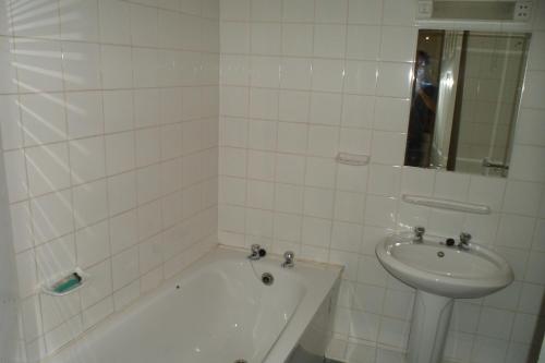 a white tiled bathroom with a tub and a sink at Severn View Hotel in Worcester