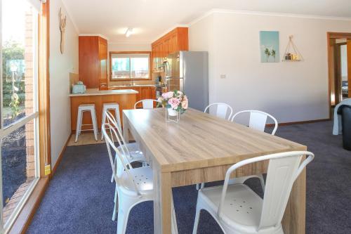 a kitchen with a wooden table and white chairs at Tee Off Milura in Mildura