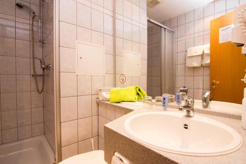 uma casa de banho com um lavatório, um chuveiro e uma banheira em Aparthotel am Rennsteig em Wurzbach