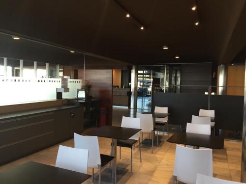 a restaurant with black tables and white chairs at Hotel America Igualada in Igualada