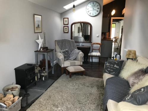 a living room with a couch and chairs and a clock at Dippy cottage in Bexhill