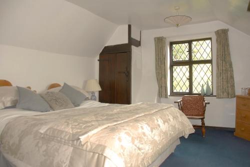 a bedroom with a large bed and a window at Cleavers Lyng 16th Century Country House in Herstmonceux