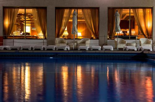 a hotel swimming pool with white chairs and a swimming pool at The Seasons Hotel -Studio & Suite in Netanya