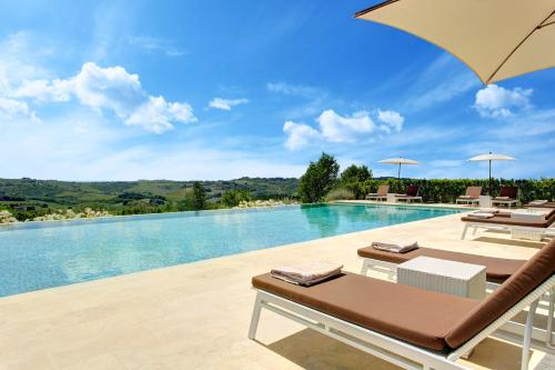 a pool with two lounge chairs and an umbrella at Villa Le Calvane in Montespertoli