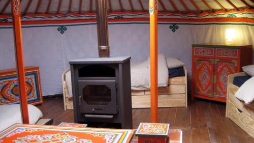 a room with a fireplace and a bed in a tent at Yourte d'Aiguevives in Céré-la-Ronde