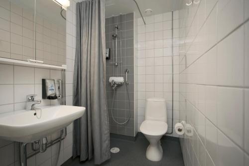 a white toilet sitting next to a sink in a bathroom at Hostel Linnasmäki in Turku