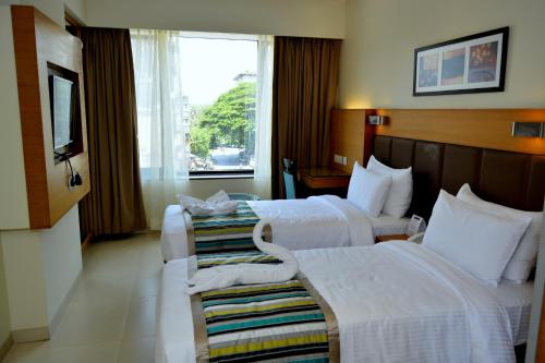a hotel room with two beds and a window at Hotel Orion Premiere in Panaji