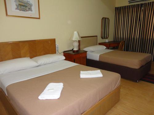 2 Betten in einem Hotelzimmer mit Handtüchern darauf in der Unterkunft Pristine Hotel in Rawang