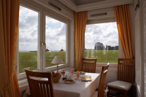 uma sala de jantar com uma mesa e uma grande janela em Hotel Beckröge em Cuxhaven