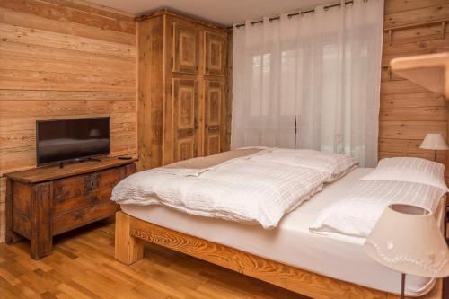 a bedroom with a bed and a flat screen tv at Appartamenti & Wellness Piero Gros in Sauze dʼOulx