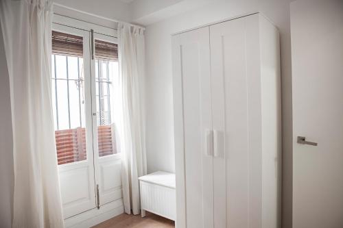 Habitación con armario blanco y ventana en Apartamento Mendoza, en Sevilla