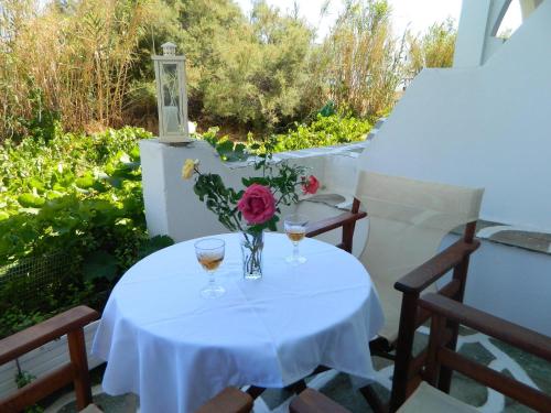 a table with two glasses and a vase of flowers at Ioanna Apartments in Agios Prokopios