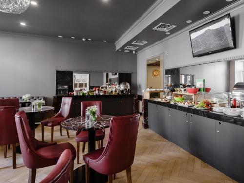 a restaurant with a bar with red chairs and a table at UNO Design Hotel in Odesa
