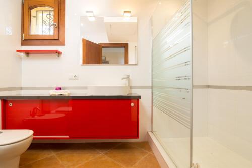 uma casa de banho com um lavatório vermelho e um WC. em Villa Son Ferragut em Sa Pobla