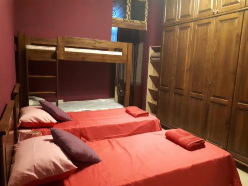 two twin beds in a room with red sheets at Nocturne Family House in Paola