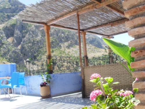 a patio with a pergola and chairs and flowers at Dar Lbakal in Chefchaouene