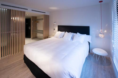 a bedroom with a large white bed and a bathroom at Hotel Mirador de Chamartín in Madrid