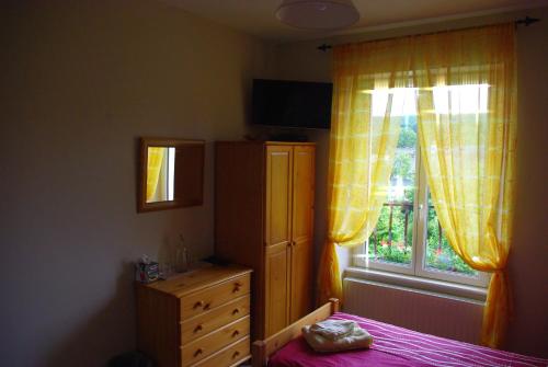 a bedroom with a bed and a dresser and a window at La Maison Celtique in Saint-Nicolas-du-Pélem