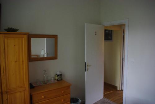 Zimmer mit Spiegel, Kommode und Tür in der Unterkunft La Maison Celtique in Saint-Nicolas-du-Pélem