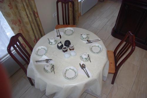 a white table with plates and utensils on it at La Maison Celtique in Saint-Nicolas-du-Pélem