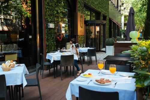 a woman sitting at a table in a restaurant at Hotel Mirador de Chamartín in Madrid