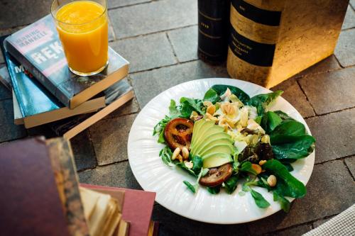 a plate of food with a salad and a glass of orange juice at Hotel Mirador de Chamartín in Madrid