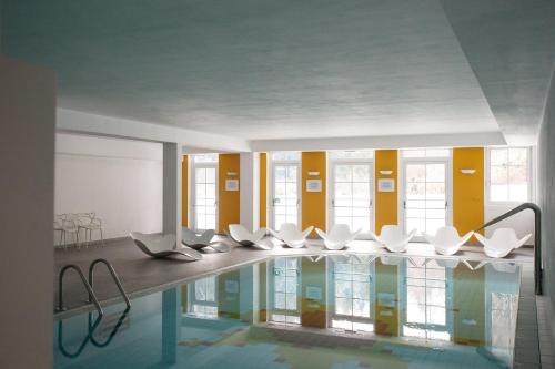 Habitación con piscina con sillas blancas. en Parkhotel Sole Paradiso, en San Candido