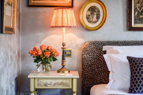 a table with a lamp and a vase of orange flowers on it at San Domenico House in London