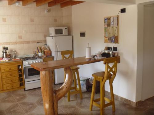 Una cocina con una mesa de madera y un refrigerador. en Cabaña Lecalau, en Lago Puelo