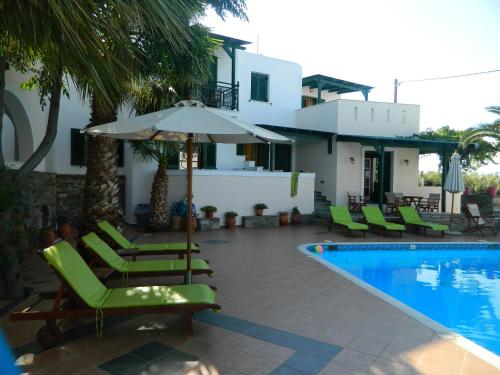 a resort with a swimming pool with chairs and an umbrella at Ioanna Apartments in Agios Prokopios