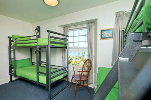 a room with bunk beds and a chair and a window at YHA Coverack in Coverack