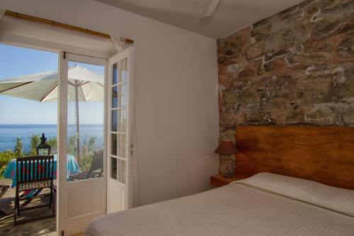 Casa de Pedra في Ribeira Quente: غرفة نوم بسرير وفناء مع مظلة