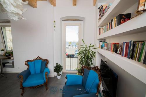 twee blauwe stoelen in een kamer met een boekenplank bij Bed & breakfast La Nassa in Taranto