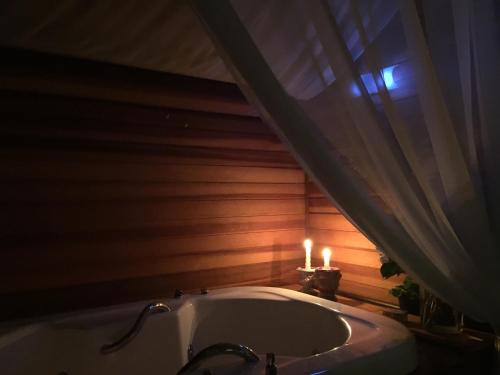 a bathroom with a tub with a candle and a window at La Réserve Suites in Monte Verde