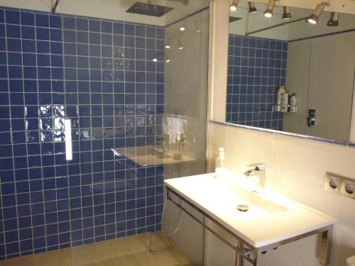 uma casa de banho em azulejos azuis com um lavatório e um espelho em Sa Lluna em Es Mercadal