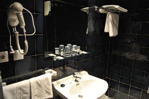 baño de azulejos negros con lavabo y teléfono en Hotel Los Angeles, en Almendralejo