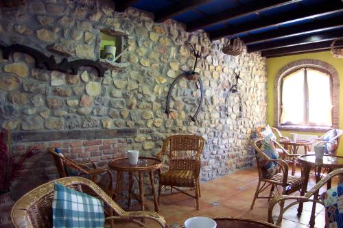 a restaurant with tables and chairs and a stone wall at Conjunto Hotelero La Pasera in Soto de Cangas