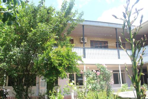 a building with a balcony and trees at Canal Hostel in Sheki