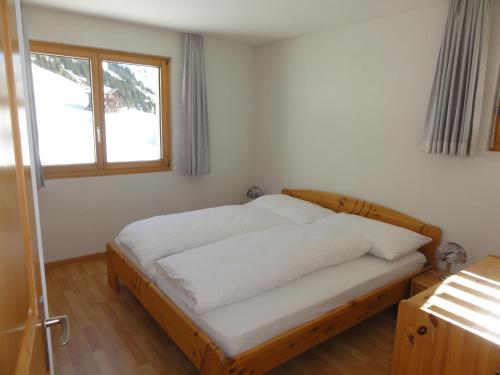 Apartment Weisshorn في ريدرالب: غرفة نوم بسرير وملاءات بيضاء ونافذة