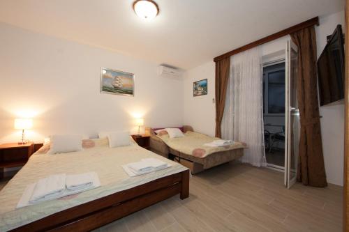 1 dormitorio con 2 camas y puerta corredera de cristal en Apartments Šarić en Baška Voda