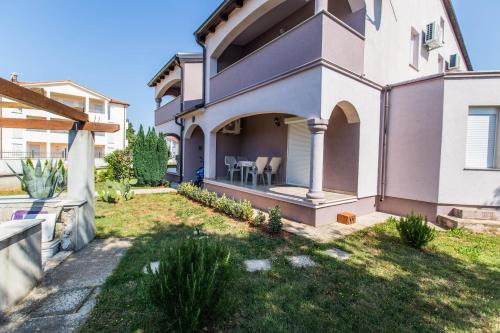 a house with a patio with chairs on the yard at Apartments Vukalovic in Medulin