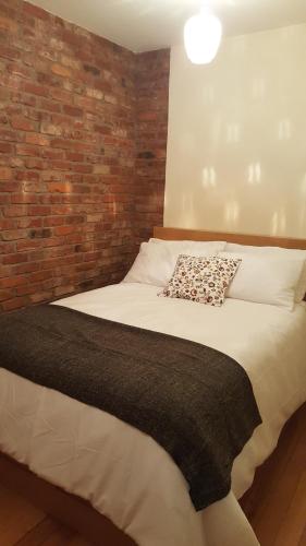 a bedroom with a bed with a brick wall at Historic Hideaway in Cork City Centre in Cork