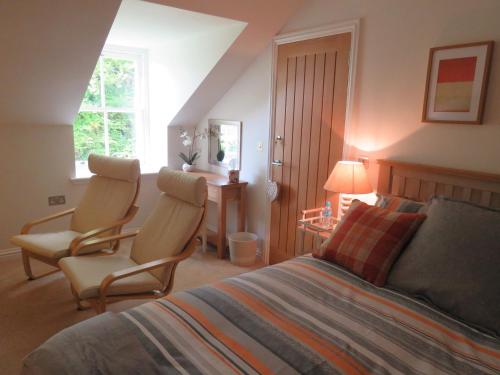 a bedroom with two chairs and a bed and a desk at The Barn @ The Coach House in Melrose