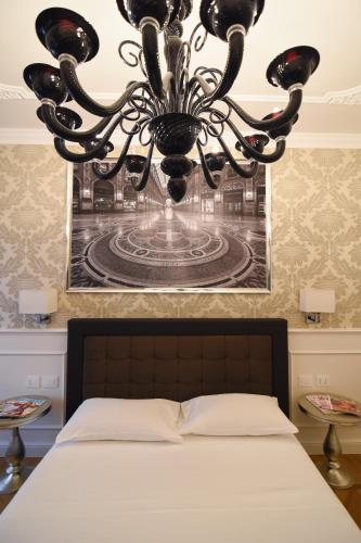 a chandelier hanging over a bed in a bedroom at Duomo Rooms in Milan
