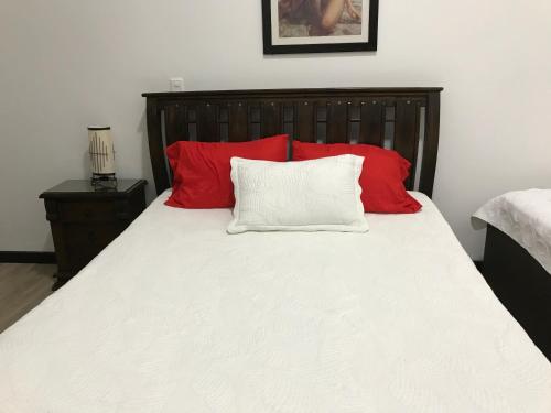 Una cama con almohadas rojas y blancas. en Hospedaje Solymar Sarie Bay, en San Andrés