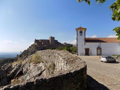 a church on a mountain with a car parked in front at Casa O Arco Alojamento Local in Marvão