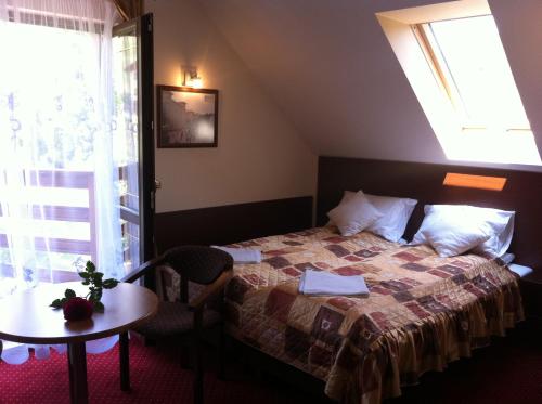 um quarto com uma cama, uma mesa e uma janela em Willa Marie em Krynica-Zdrój