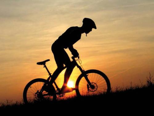 a man riding a bike in front of the sunset at Hotel Gianna in Roseto degli Abruzzi