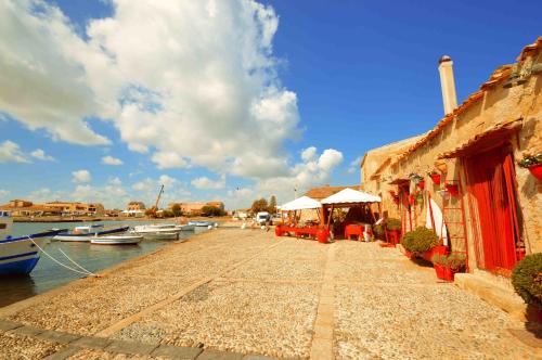 a walkway next to a building with boats in the water at Yachting Apartment in Marzamemi