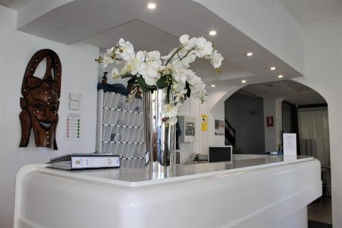 a vase filled with white flowers on a counter at Hotel Marbel in Can Pastilla
